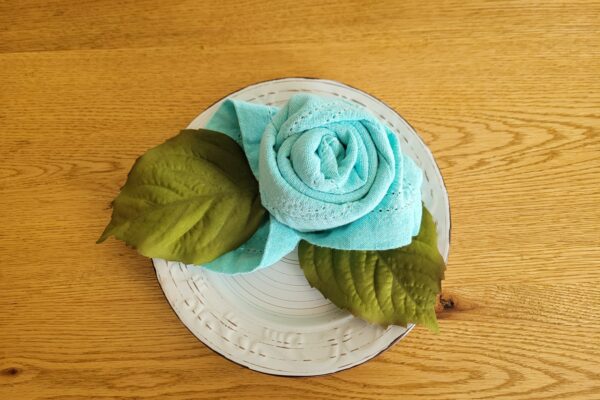 Turquoise napkin folded into a rose