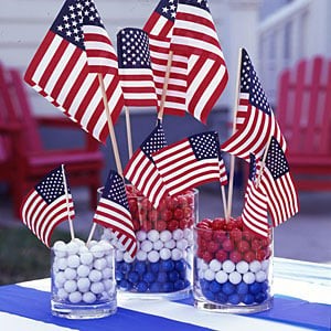 Three clear glass jars filled with red, white, and blue gumballs. Small American flags are inserted in each one.