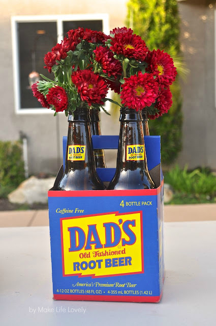 Four-pack of Dad's root beer bottles filled with red mums.