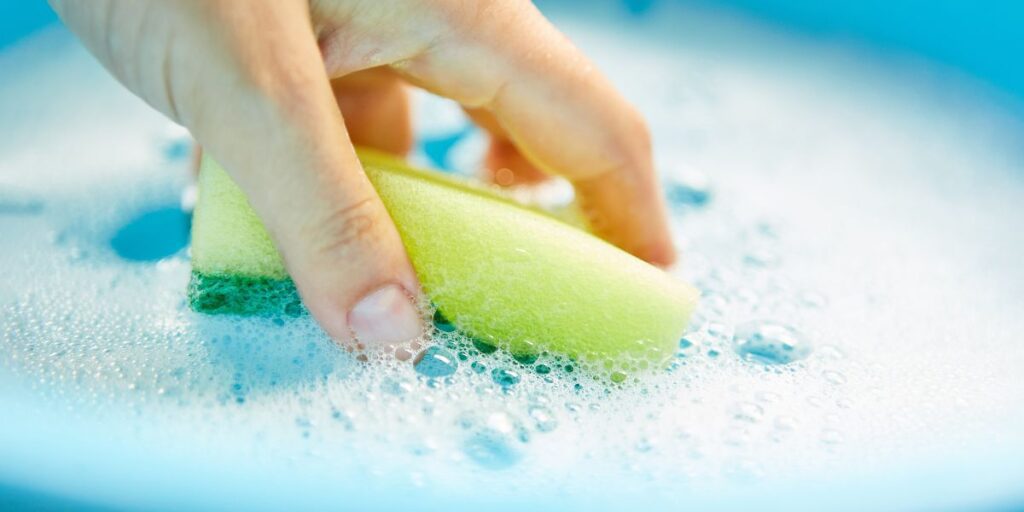 Hand holding a sponge in soapy water.