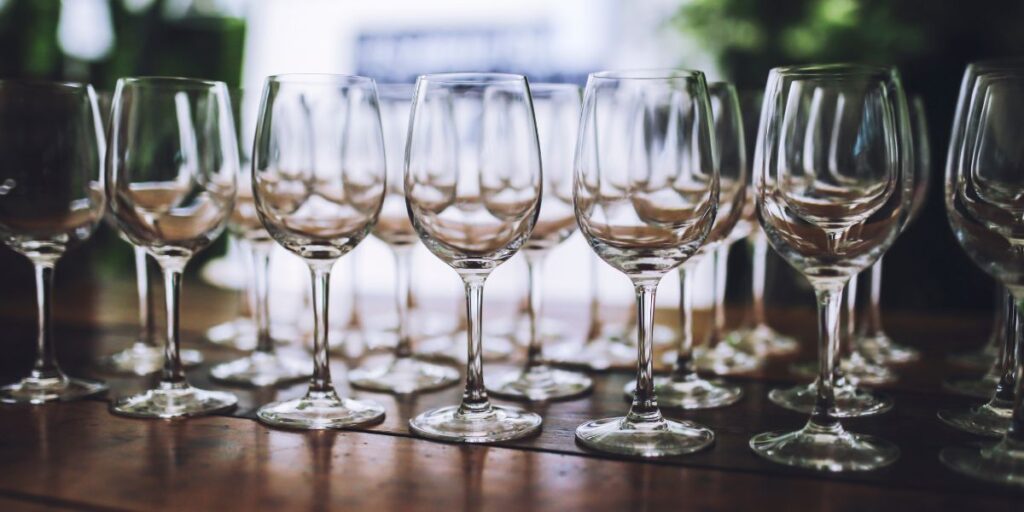 Wine glasses arranged on a wooden table outside.