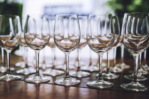 Wine glasses arranged on a wooden table outside.