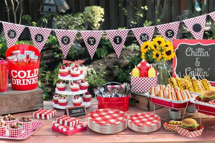 Buffet table with a BBQ Time banner, hot dogs, grilled corn, red and white checked plates and napkins, and sunflowers.