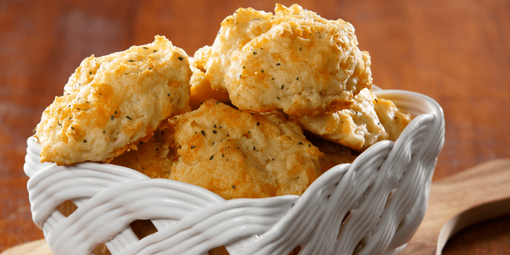 White ceramic basket holding a batch of Cheddar Bay Biscuits