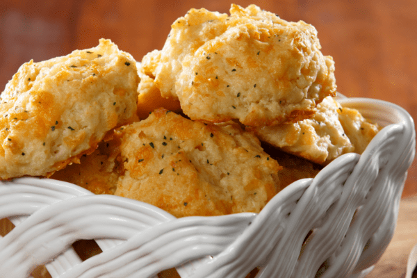 White ceramic basket holding a batch of Cheddar Bay Biscuits