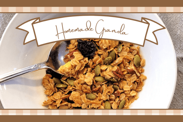 White ceramic bowl of granola with a spoon in it on a gray linen napkin