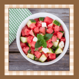 Watermelon-Salad-Recipe | The Granite Acorn Cucumber watermelon salad garnished with mint leaves and topped with feta cheese cubes in a white bowl