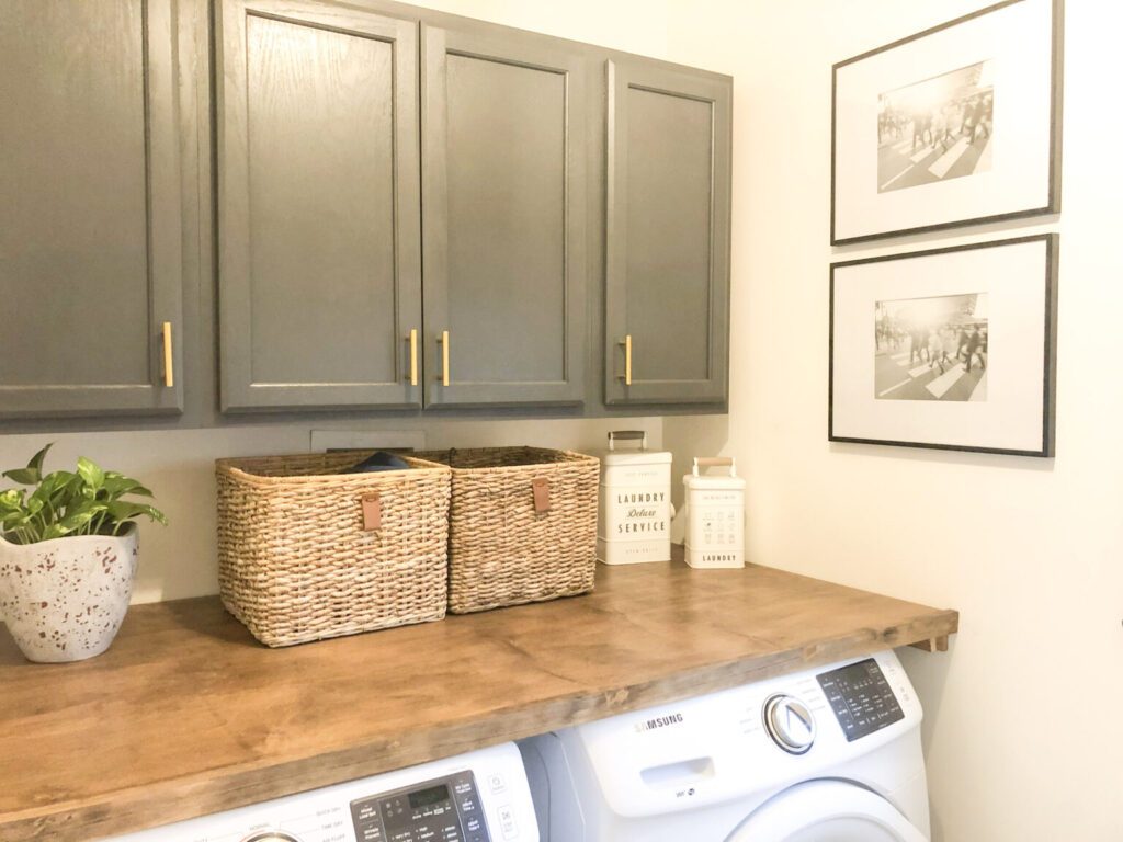 Wooden countertop mounted to a wall that sits over a front load washer and dryer.