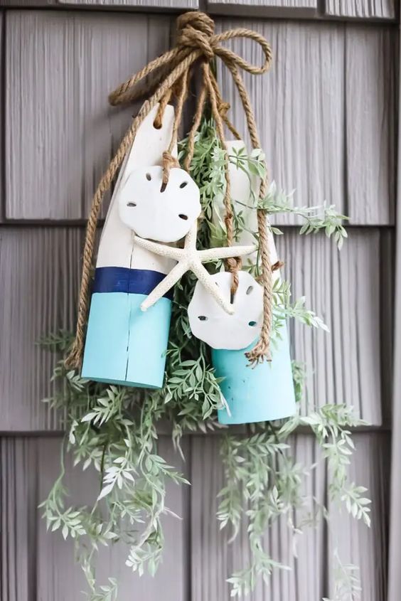 Wooden buoys tied with sand dollars and starfish hanging on shingled siding.