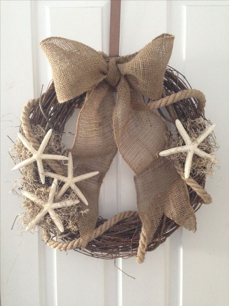 Grapevine wreath with burlap bow, moss, and starfish hanging on a white door.