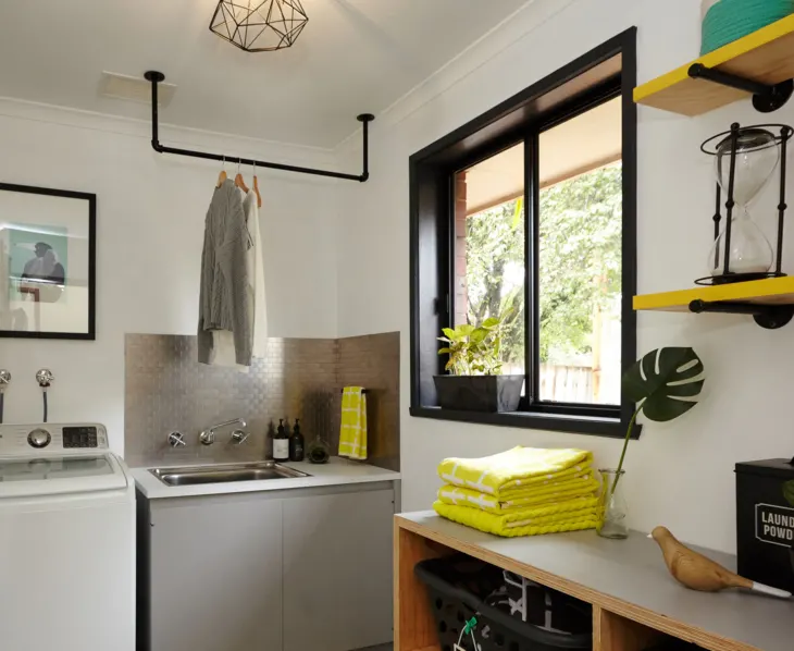 Laundry room featuring a ceiling mounted rod made from pipe fittings and painted black.