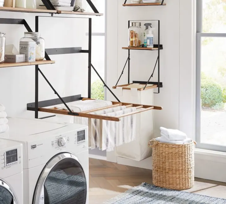 White laundry room showing black metal and wood fold out drying racks mounted to the wall.