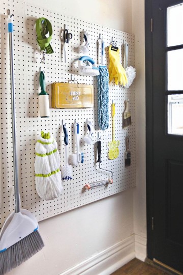 Laundry room wall with pegboard mounted to it. The board is painted white and outfitted with hooks for hanging leashes, lint rollers, scrub brushes, scissors, and the like.