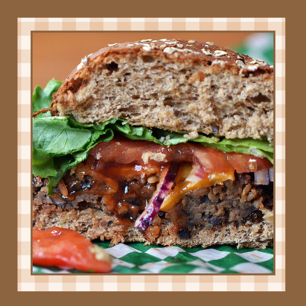 Black-Bean-Burger-Recipe | The Granite Acorn Black bean burger cut in half Burger is on a whole grain bun with lettuce and tomato