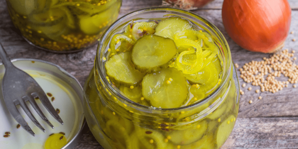 Open jar of pickles on a wood table