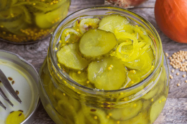 Open jar of pickles on a wood table