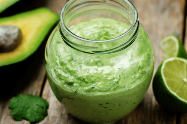 Jar of cilantro lime dressing on a wooden table