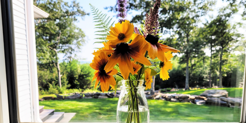 Clear vase with assorted wildflowers on a windowsill