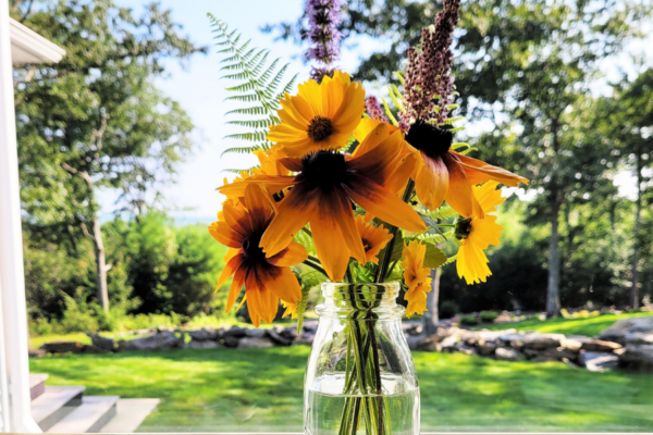 Clear vase with assorted wildflowers on a windowsill