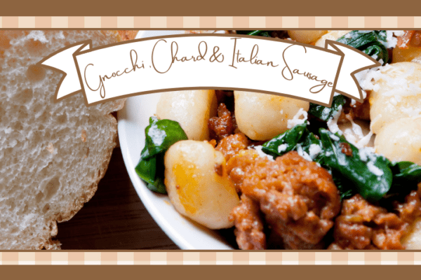 Bowl of gnocchi chard and italian sausage with bread on the side