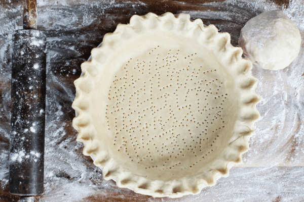 Single crust pie dough in a pie plate on a floured board