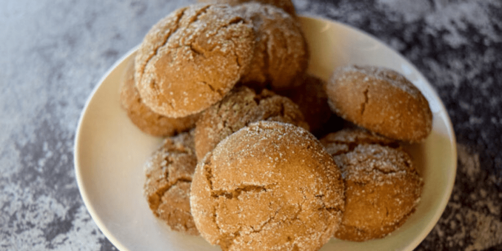 White plate filled with crinkle top cookies on a gray counter.