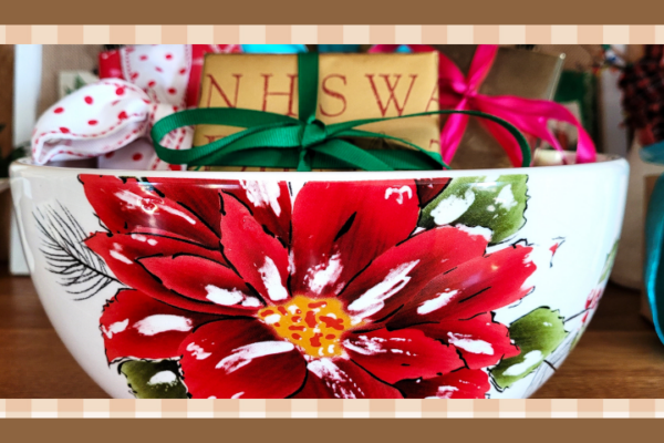 White bowl with a poinsettia painted on it and filled with wrapped gifts