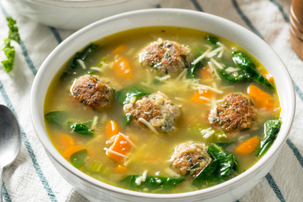 Bowl of wedding soup on a blue and white striped kitchen towel.