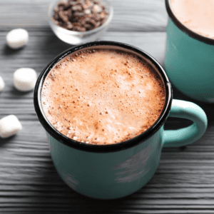 A turquoise blue mug of hot cocoa on a gray wood table