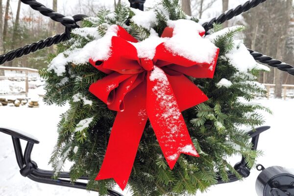 Balsam wreath with red bow dusted with snow