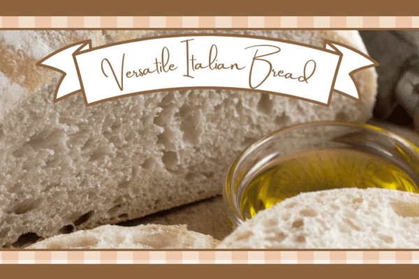 Closeup of a loaf of italian bread with some sliced off It's on a wood board with a glass dish of olive oil next to it