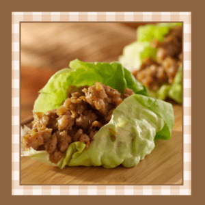 Closeup of a leaf of butter lettuce filled with a savory chicken like filling It's presented like a taco