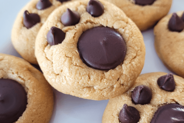 PB Paw Prints-Banner | The Granite Acorn Plate of peanut butter cookies with paw prints pressed into the tops using a chocolate wafer and three chocolate chips