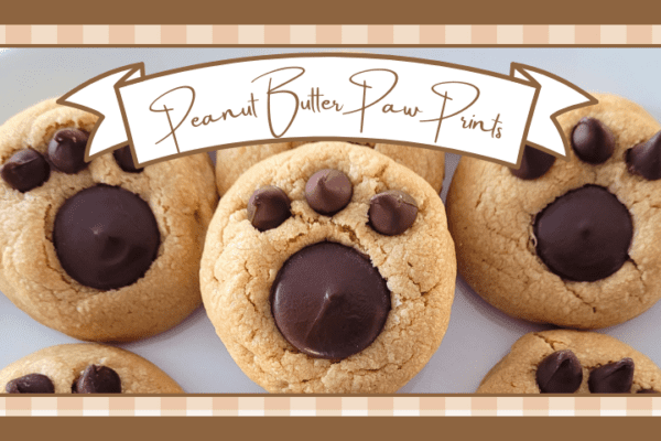 Plate of peanut butter cookies with paw prints pressed into the tops using a chocolate wafer and three chocolate chips