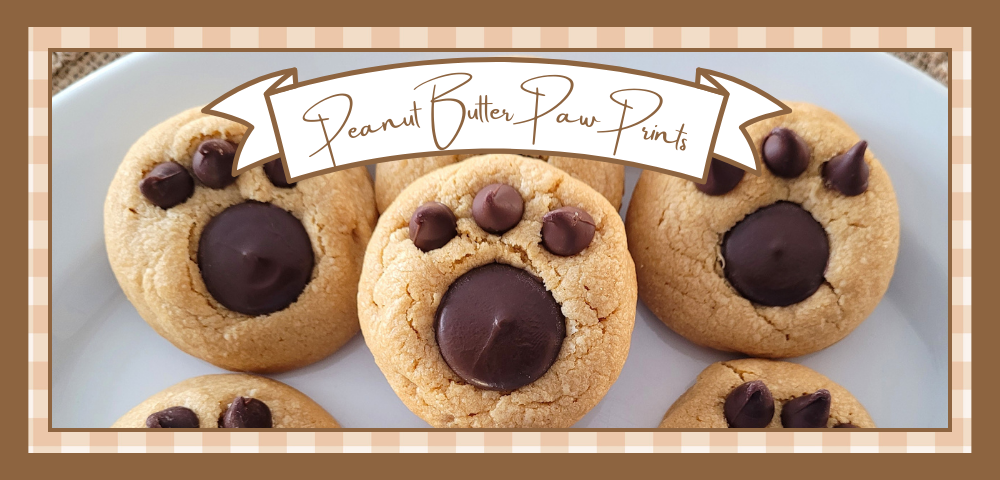 Paw-Print-Cookies-Banner | The Granite Acorn Plate of peanut butter cookies with paw prints pressed into the tops using a chocolate wafer and three chocolate chips