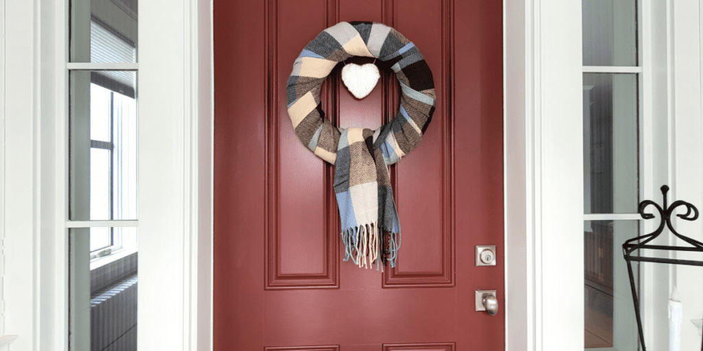 Blue, brown, and cream plaid wreath with a cream heart on a red door.