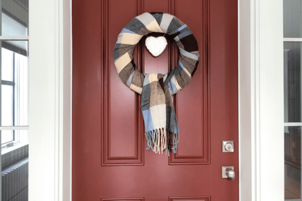 Blue, brown, and cream plaid wreath with a cream heart on a red door.