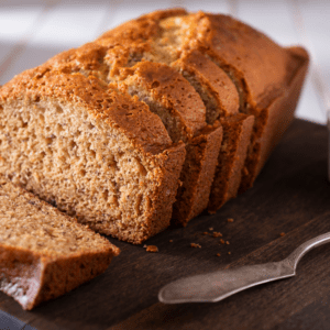 Loaf of banana bread, sliced on a cutting board.