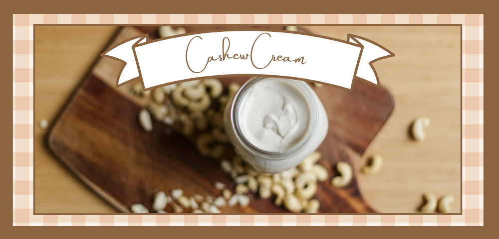 Jar of cashew cream on a wooden board with whole cashews scattered around it.