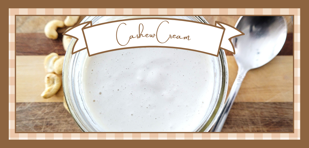 Jar of cashew cream on a wooden board with whole cashews scattered around it.