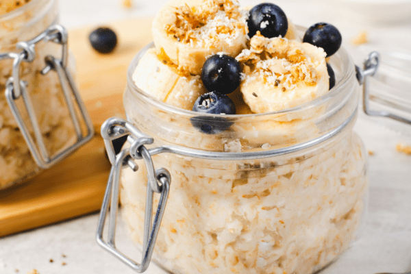 Overnight Oats-Banner | The Granite Acorn Jar of overnight oats topped with blueberries and bananas
