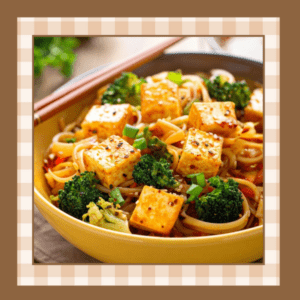 Closeup of bowl with noodles, tofu cubes, and broccoli.