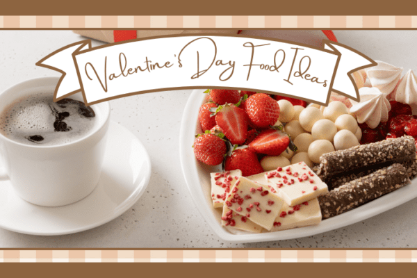 Cup of coffee next to a heart shaped platter filled with strawberries and sweets