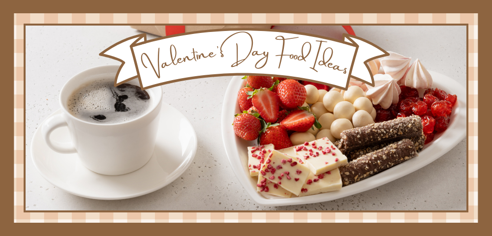 Cup of coffee next to a heart shaped platter filled with strawberries and sweets