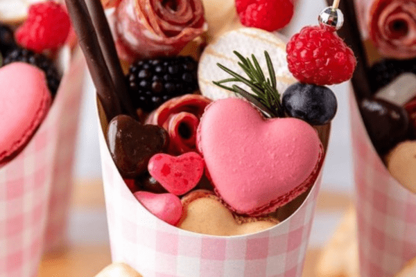 Valentine's-Foods-Banner | The Granite Acorn Pink and white gingham cups with an assortment of fruit cheese macarons and other sweets
