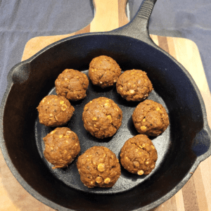 Cast iron skillet with vegan meatballs on a wooden cutting board