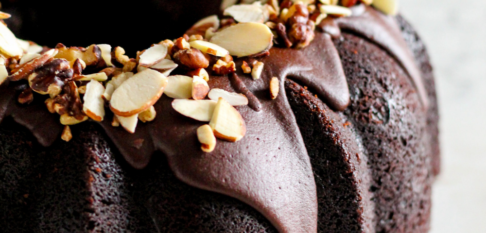 Closeup of a chocolate bundt cake with chocolate glaze sprinkled with chopped nuts