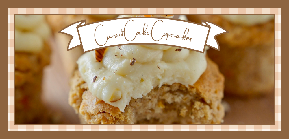 Closeup of a carrot cake cupcake with cream cheese frosting and a sprinkle of nuts. A bite has been taken out of it.