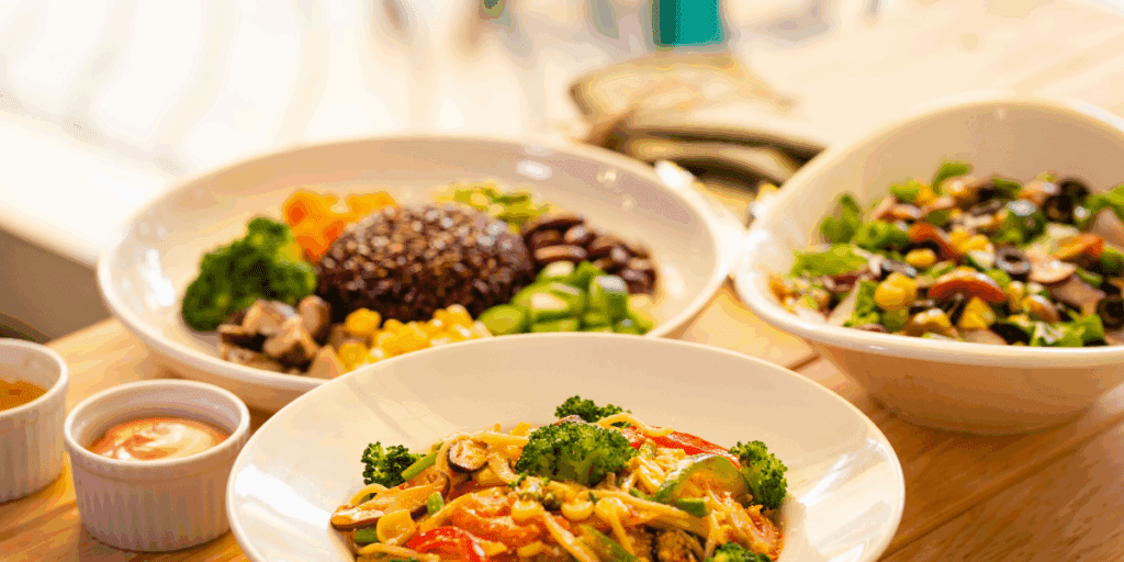 Three white bowls with vegan dishes in each.