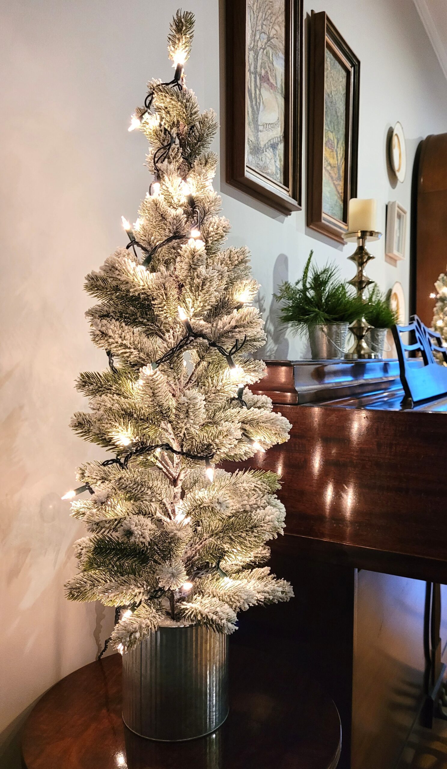 Closeup of a lit flocked tree next to a piano